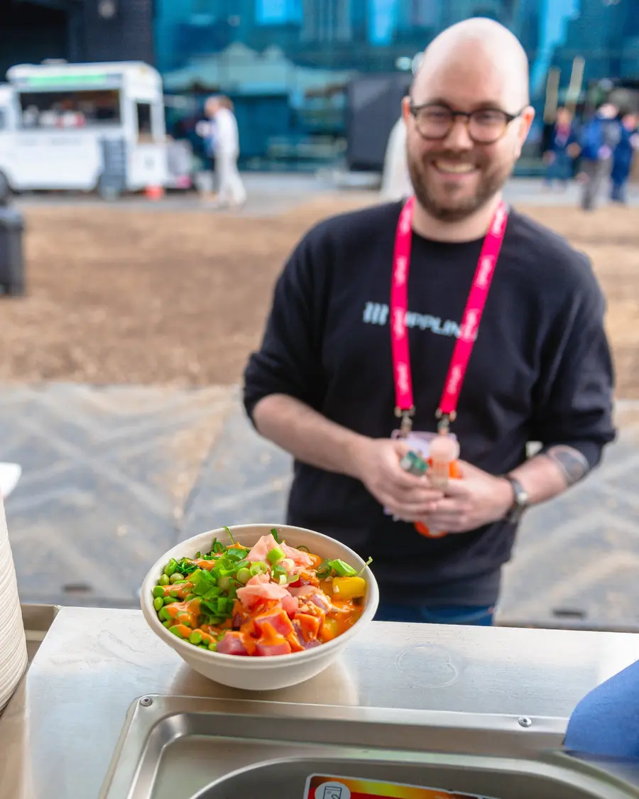 A smiling event guest waiting for his tuna poke bowl at the Peeld truck counter
